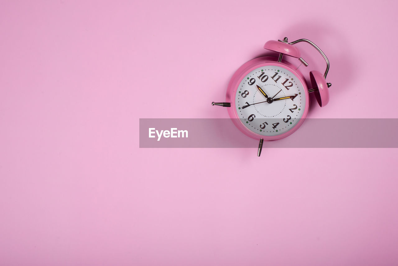 CLOSE-UP OF CLOCK AGAINST PINK BACKGROUND