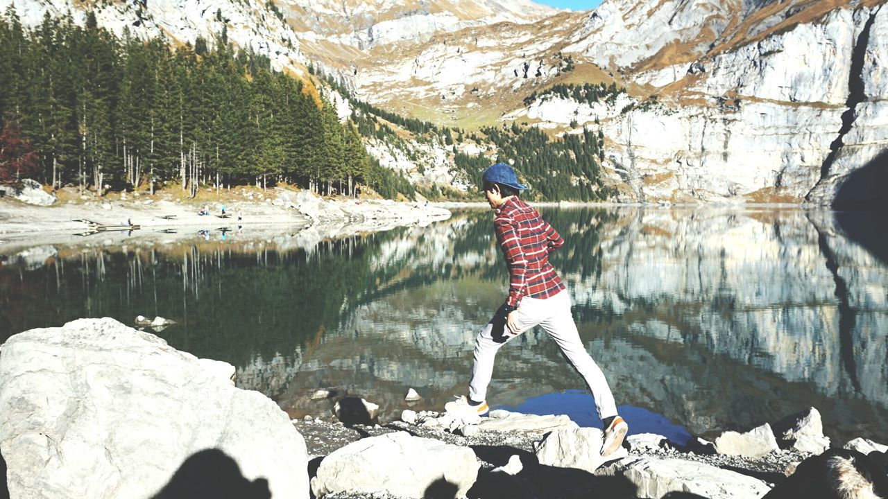 Young man walking on rocks by oeschinen lake