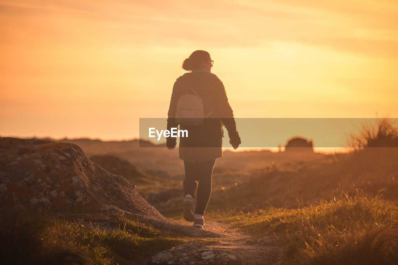 Woman walking at sunset in corrubedo natural park, galica, spain