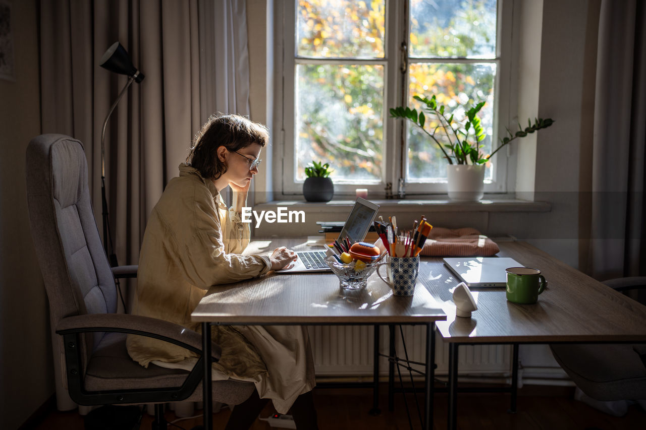 Pensive teenager reading text in laptop, studying online, working as freelancer, writer, tutor