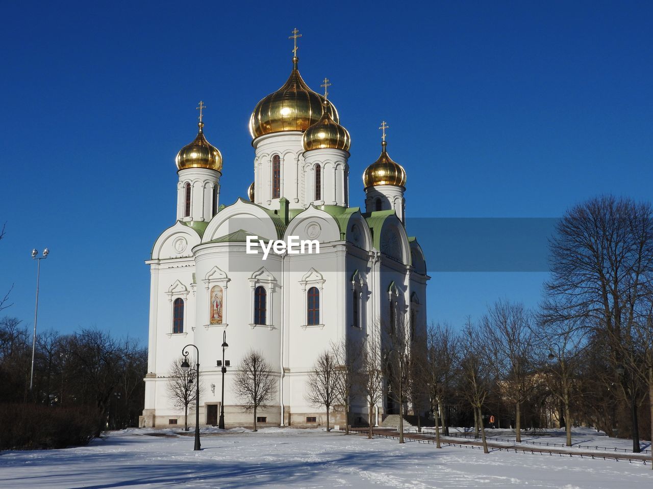 Church by building against clear blue sky during winter