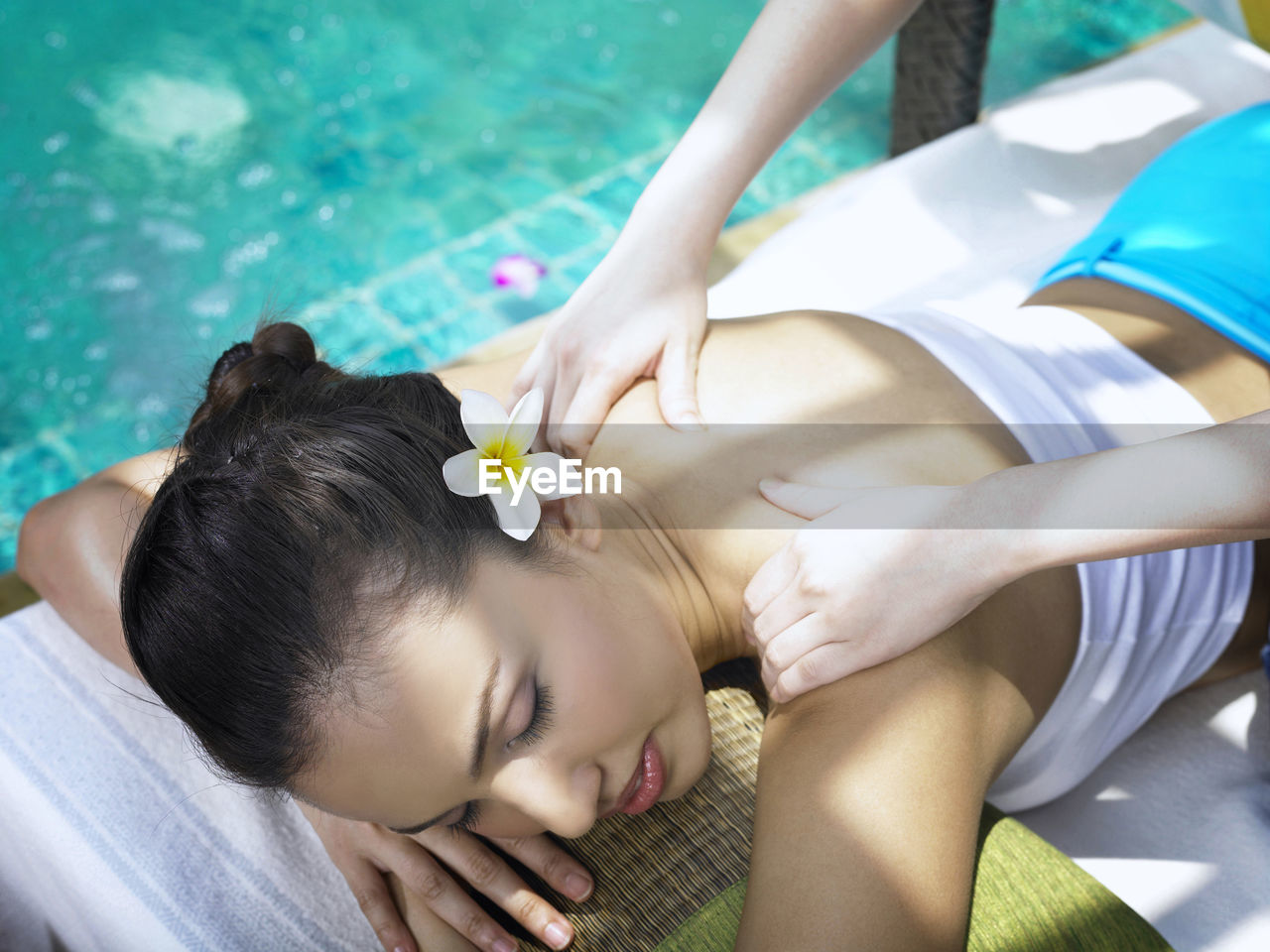 Cropped hands of woman massaging customer at poolside
