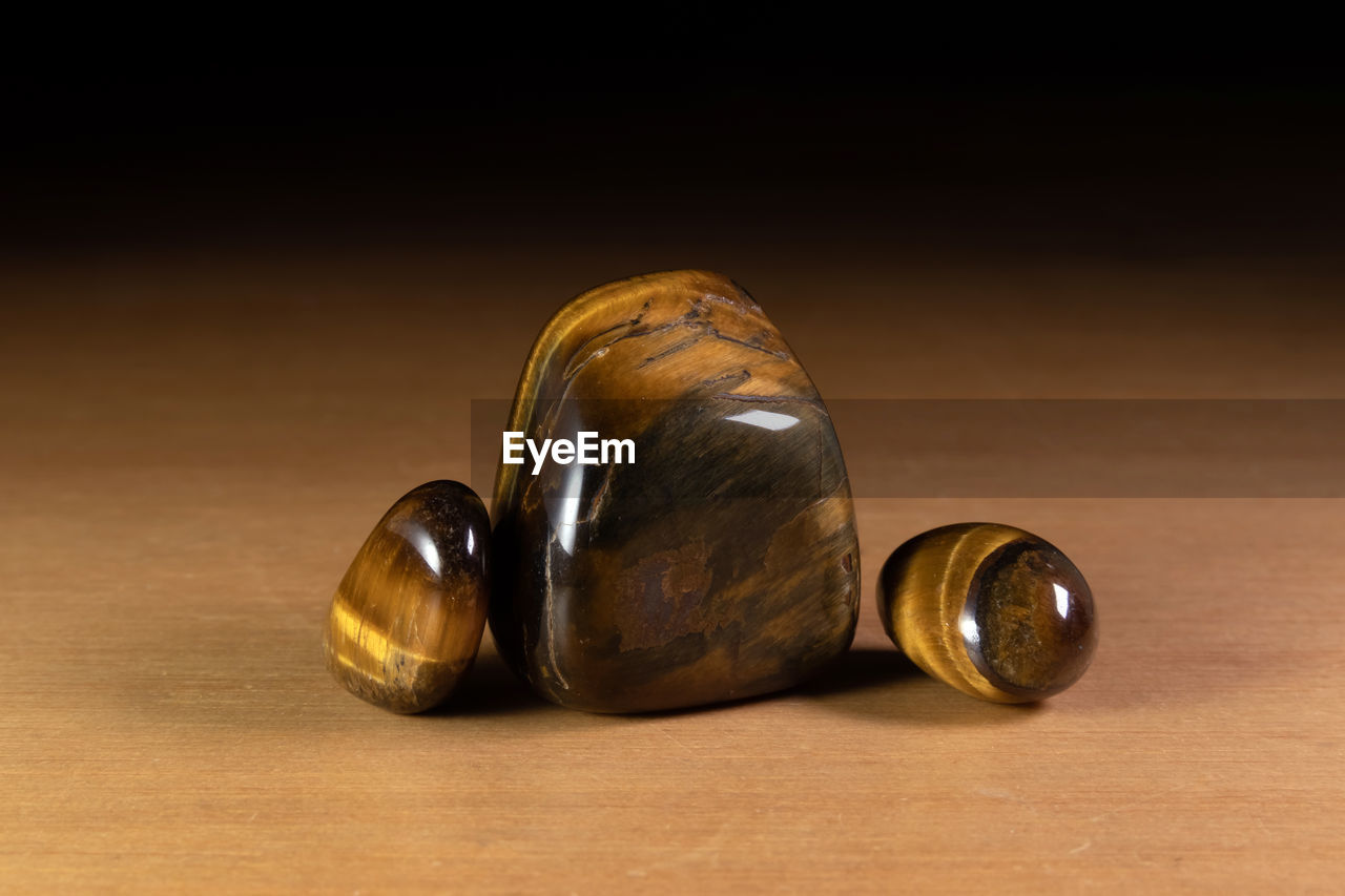 Polished tiger eye chatoyant gemstones over a wooden table. specimens from spain