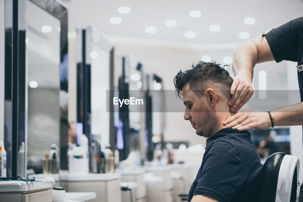 Cropped hands of barber giving massage to customer at salon