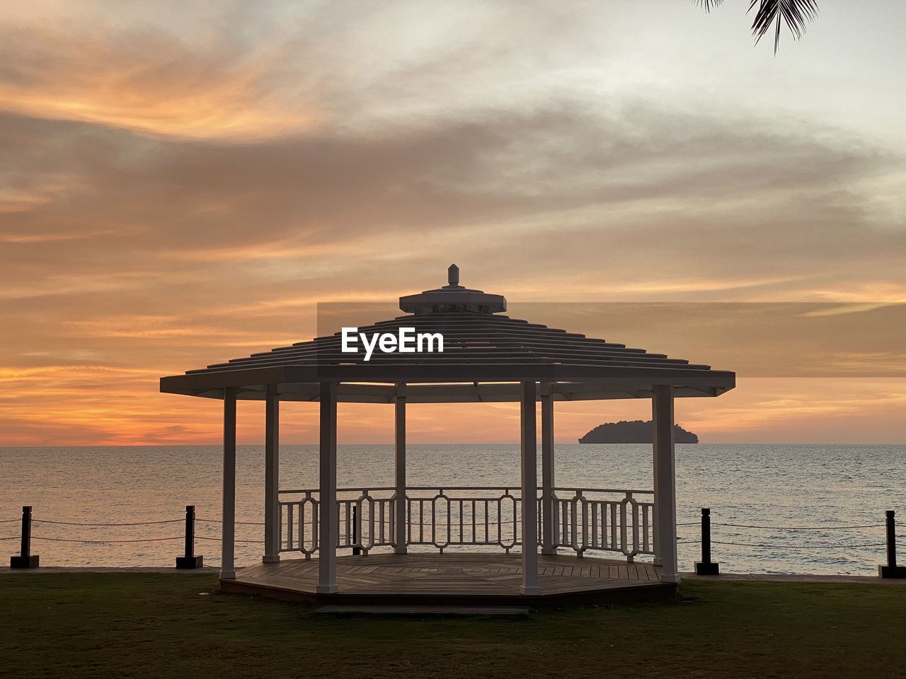 Gazebo on beach against sky during sunset