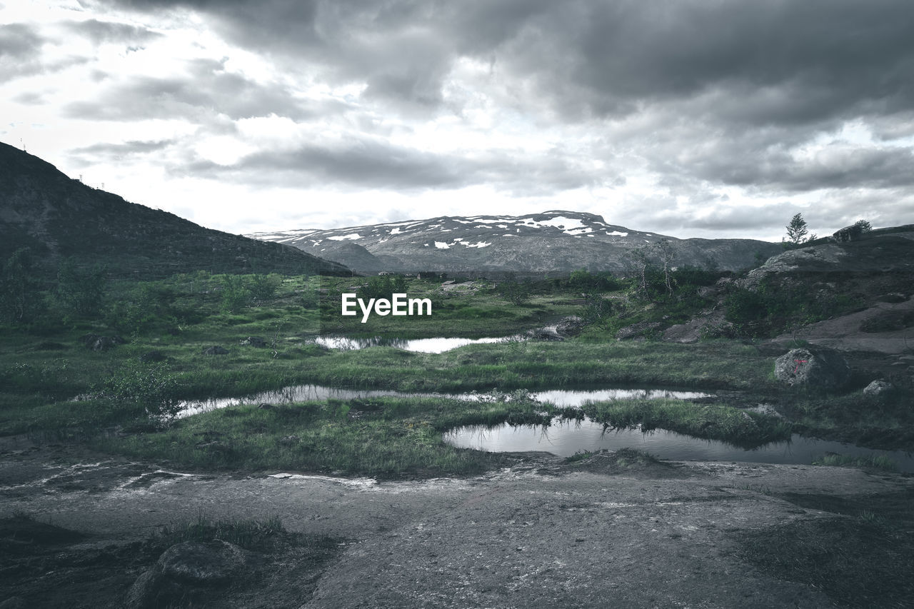 SCENIC VIEW OF MOUNTAINS AND LAKE AGAINST CLOUDY SKY