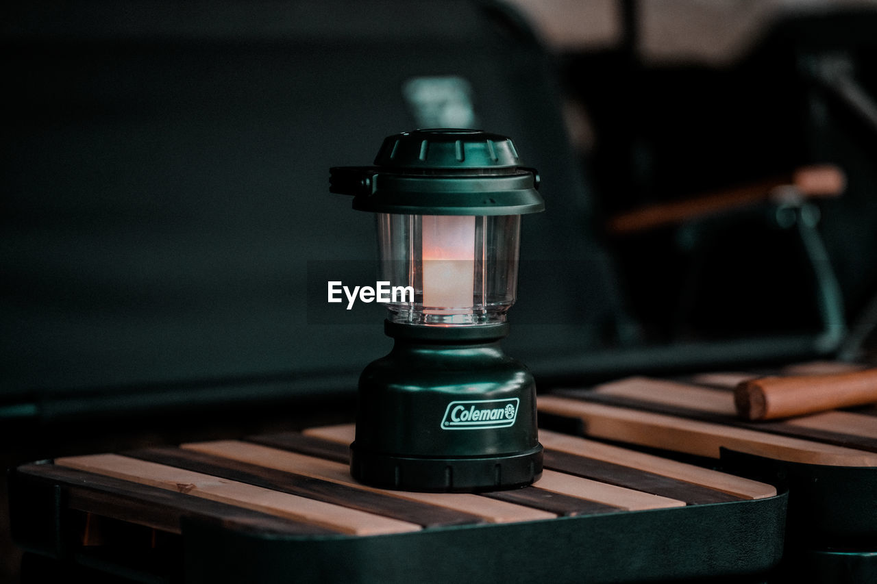 CLOSE-UP OF ILLUMINATED ELECTRIC LAMP ON TABLE IN ROOM