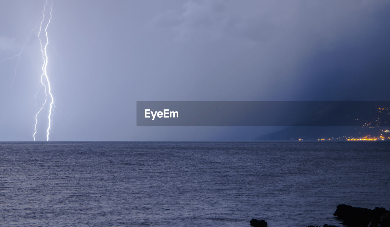 Lightning over sea against sky at night