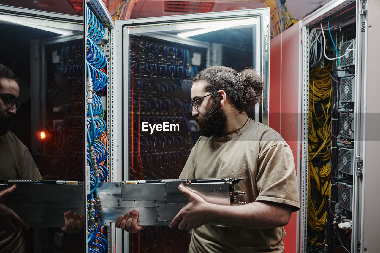 Technician inserting machine part in server at data center