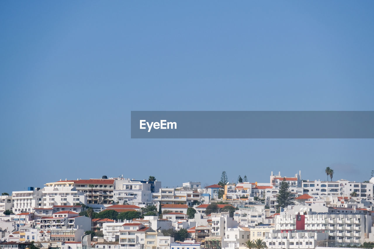 Buildings in city against clear blue sky