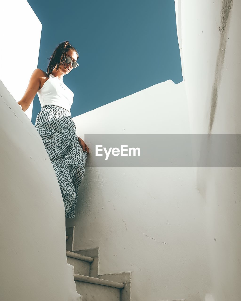 Young woman moving down on staircase against wall