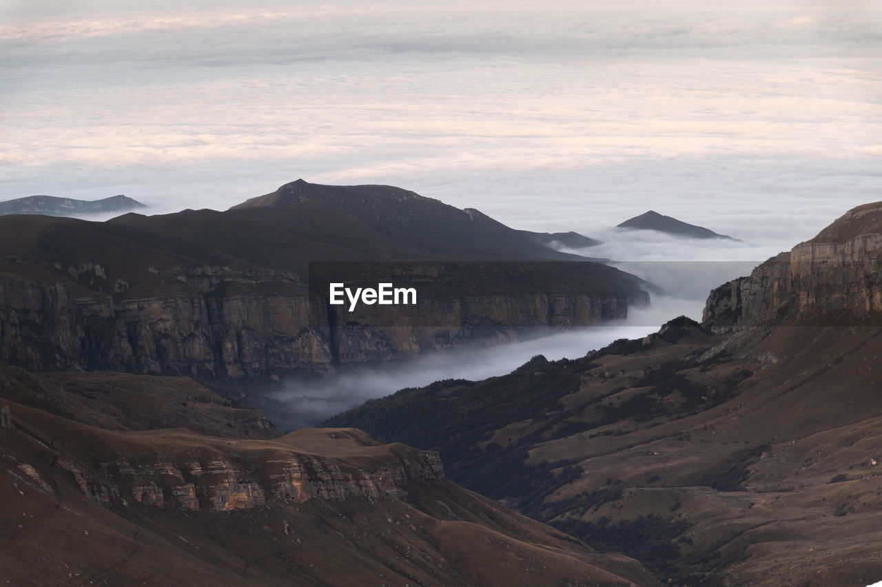 Mountains in the clouds at sunset. aerial view of a mountainous rocky range in the fog. beautiful