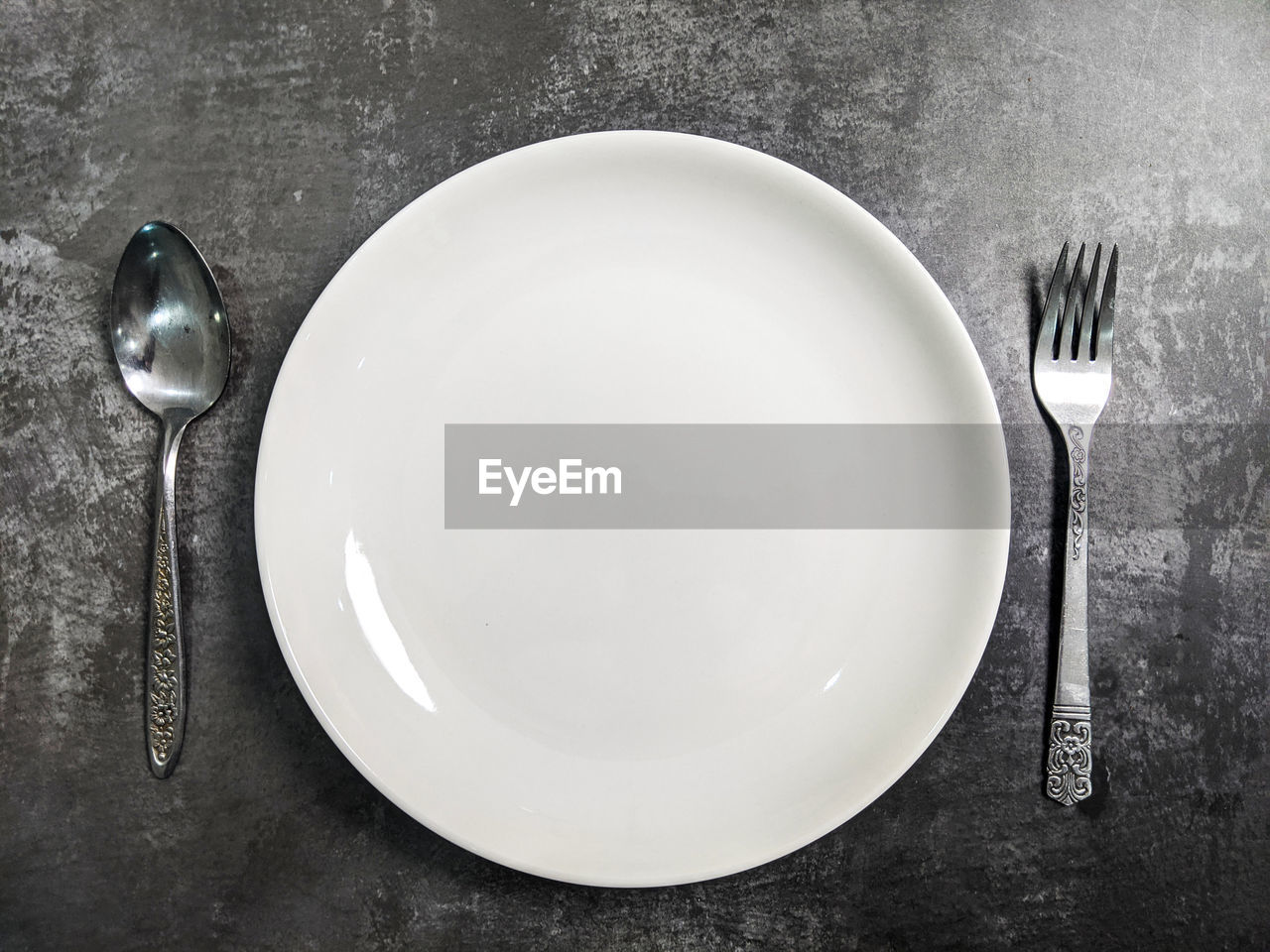 High angle view of empty plate with fork and spoon on table