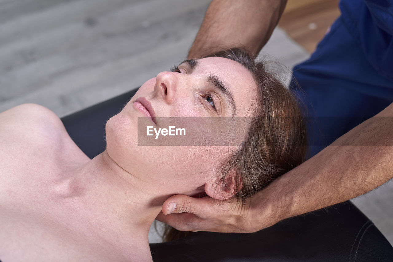 High angle view of man giving osteopath treatment to woman lying at clinic
