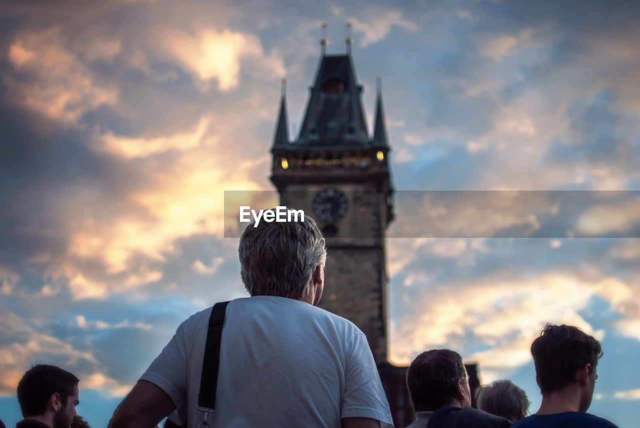 Rear view of people at church against cloudy sky during sunset