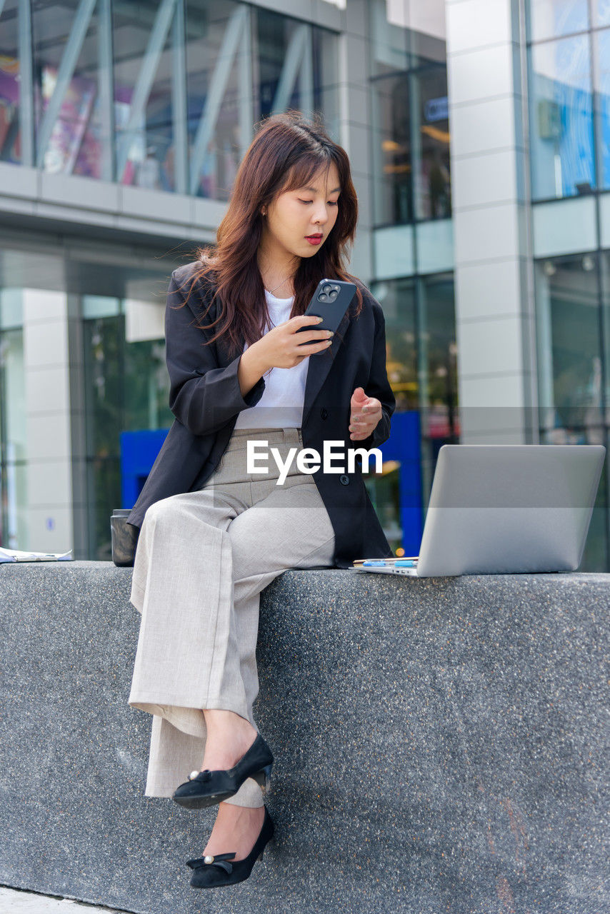 young woman using mobile phone while sitting on staircase