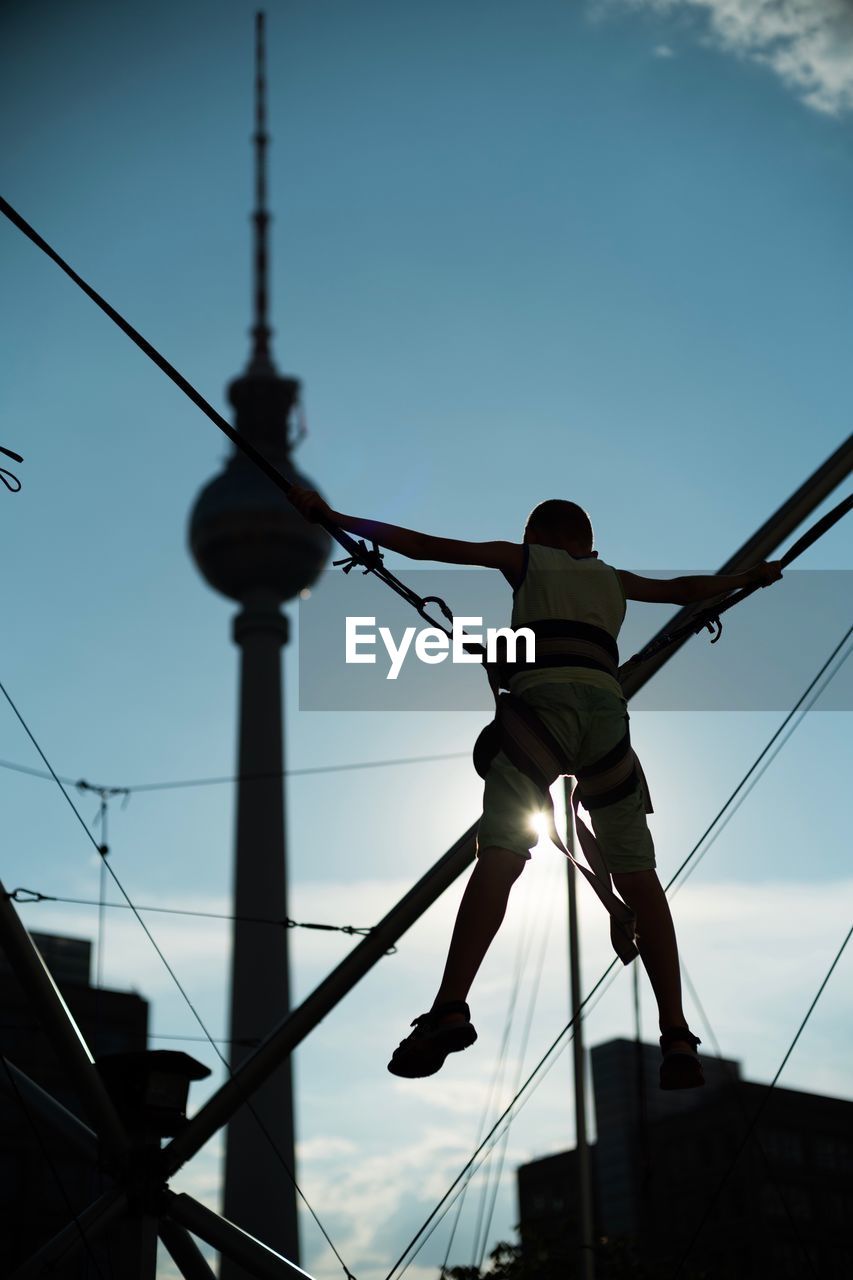 Rear view of boy on bungee trampoline with fernsehturm in background