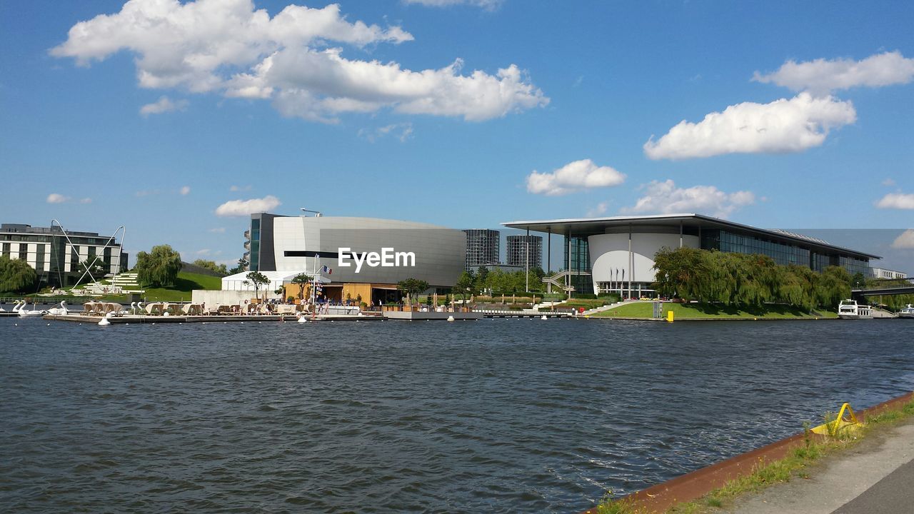 River by modern buildings against sky