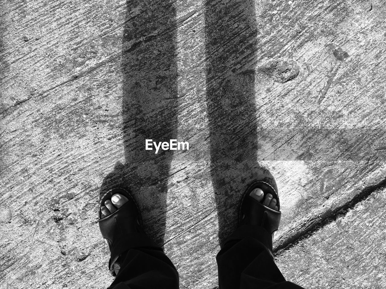 Low section of man standing on concrete path