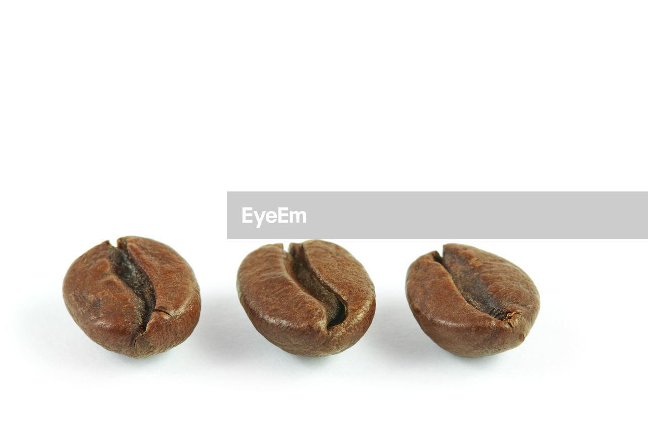 Close-up of roasted coffee beans against white background