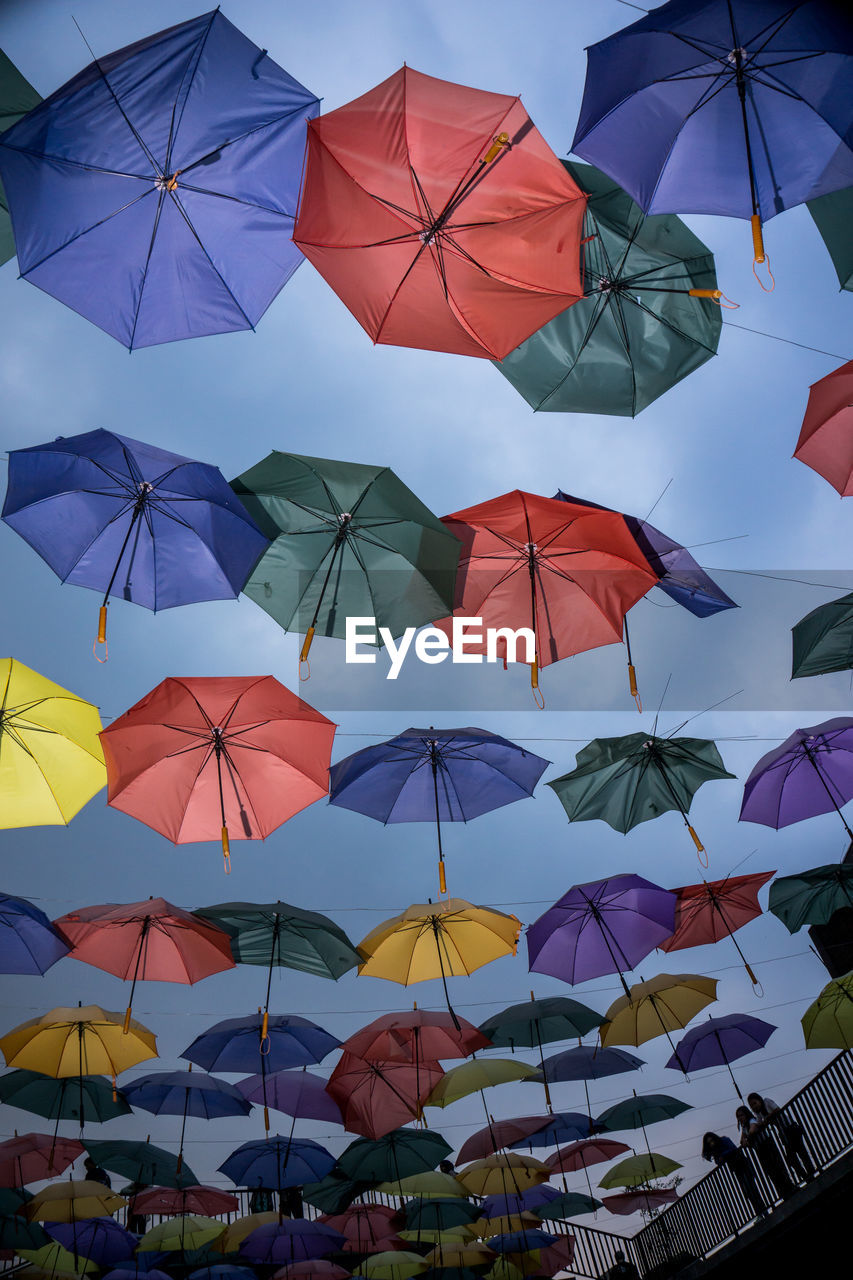 Low angle view of colorful umbrellas hanging against sky