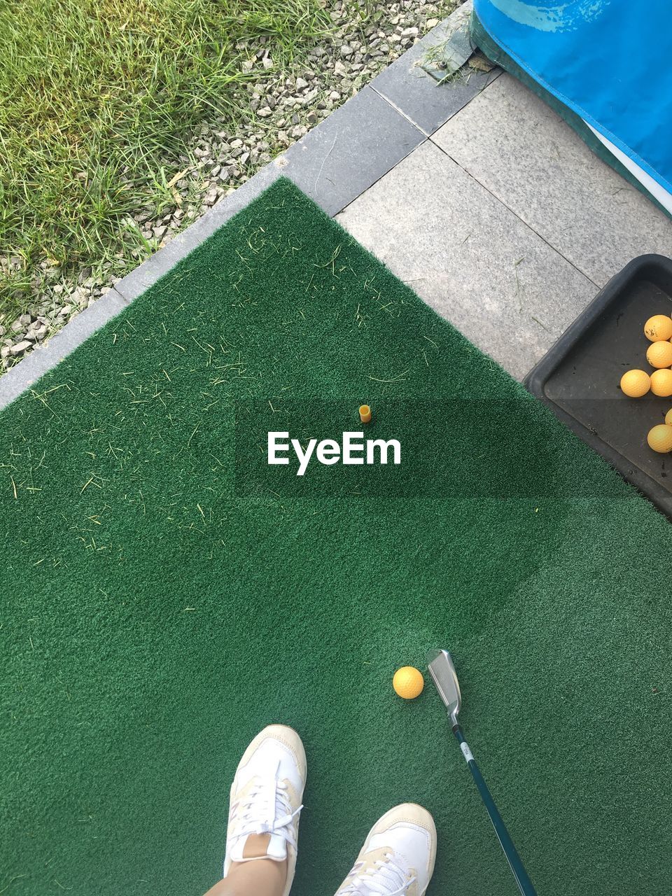 Low section of man standing by ball on golf club on turf