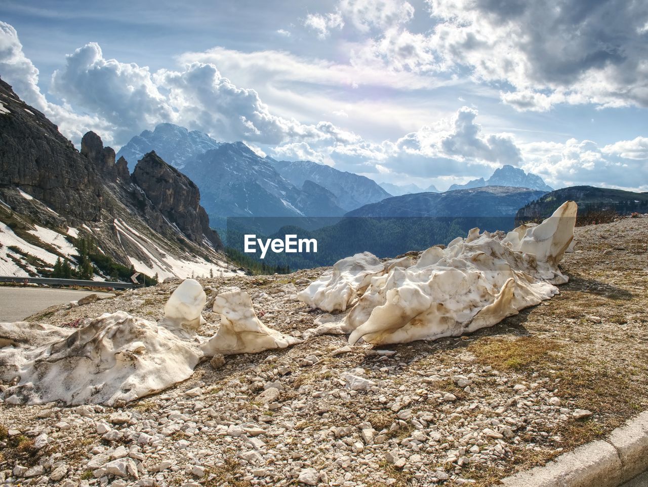 The rest of dirty snow at road in spring high mountains. spring alps mountains touching cloud sky