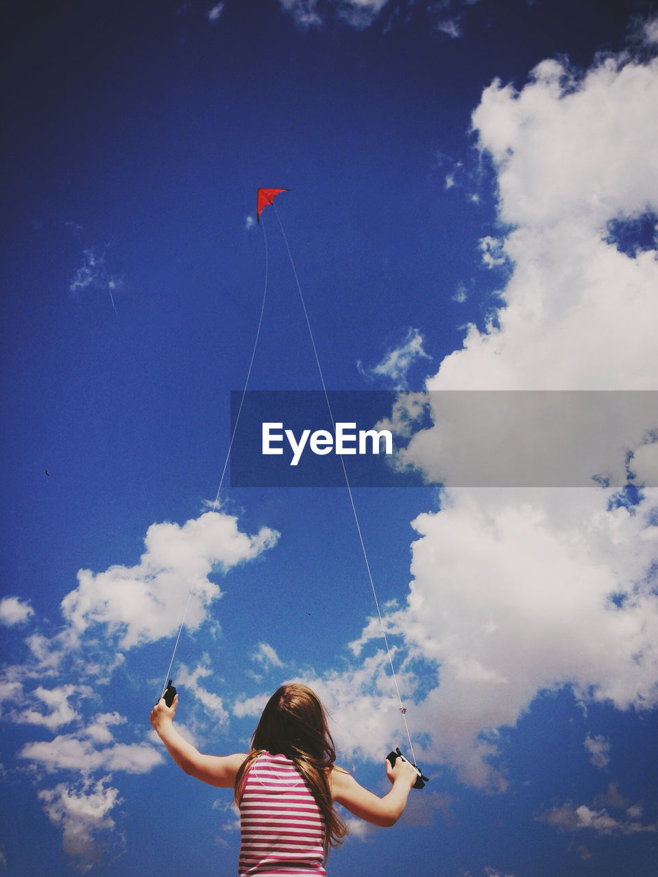 Low angle view of girl flying kite against sky