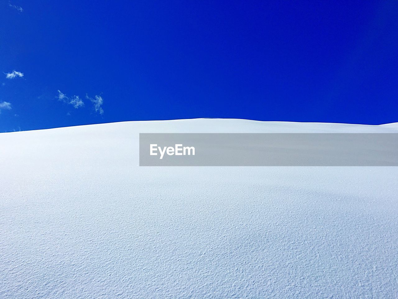 Snow covered landscape against blue sky