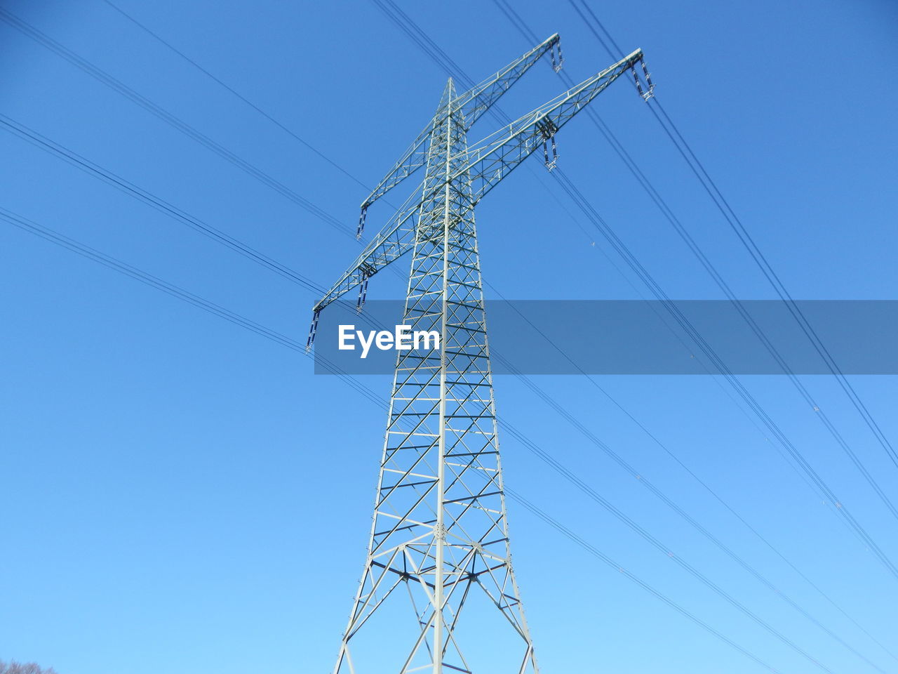 Low angle view of electricity pylon against blue sky