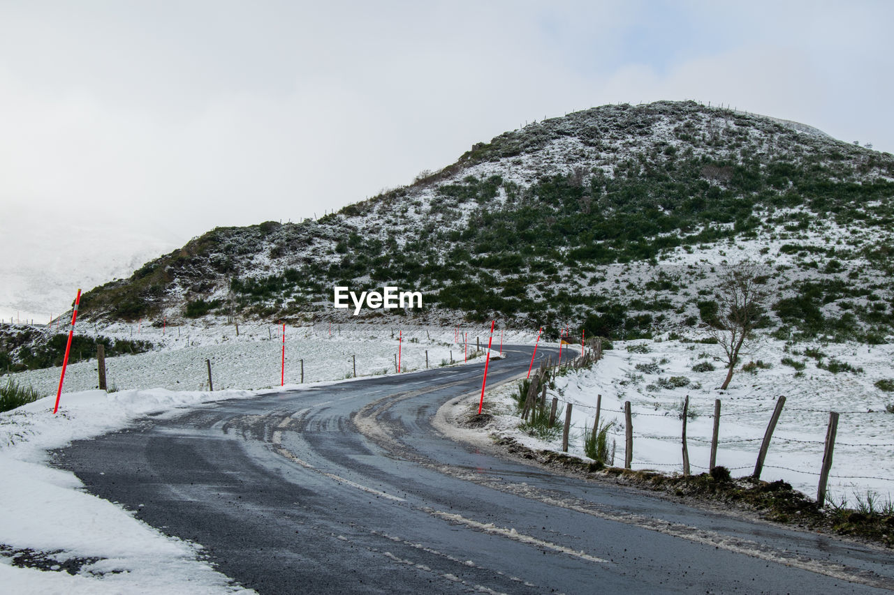 Road by mountain against sky during winter