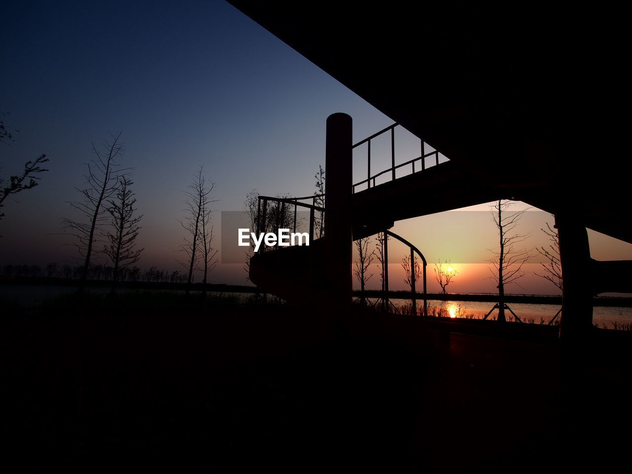 Silhouette bridge against clear sky during sunset