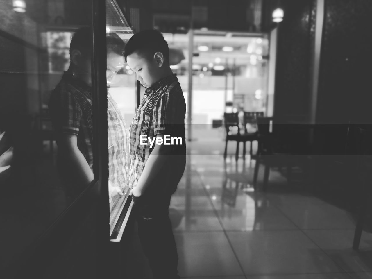 Side view of boy looking at display cabinet in restaurant