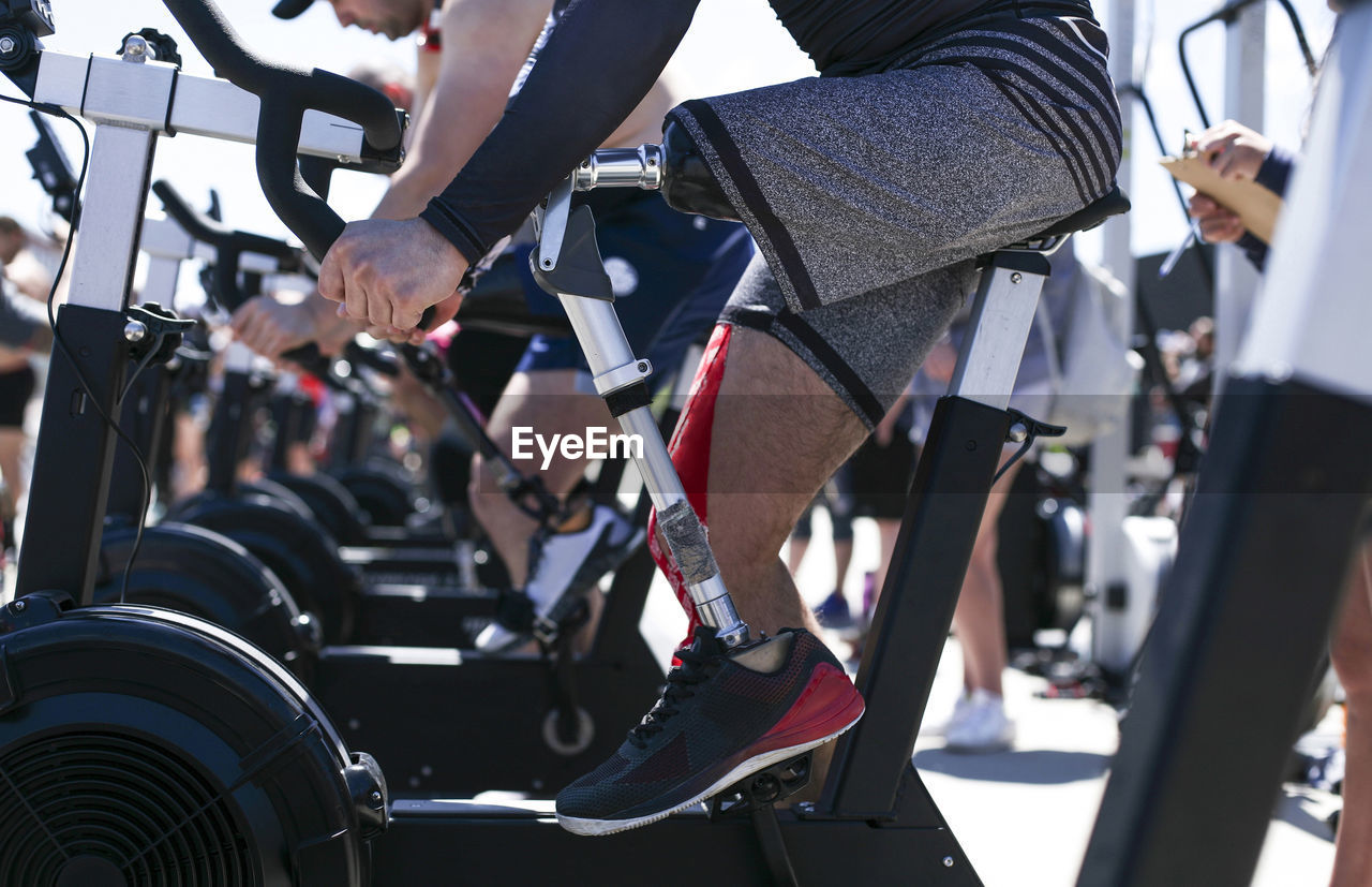 Low section of adaptive athlete exercising on exercise bike outdoors