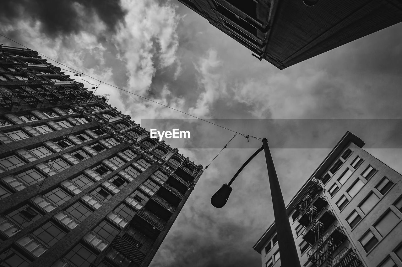 LOW ANGLE VIEW OF MODERN BUILDINGS AGAINST CLOUDY SKY