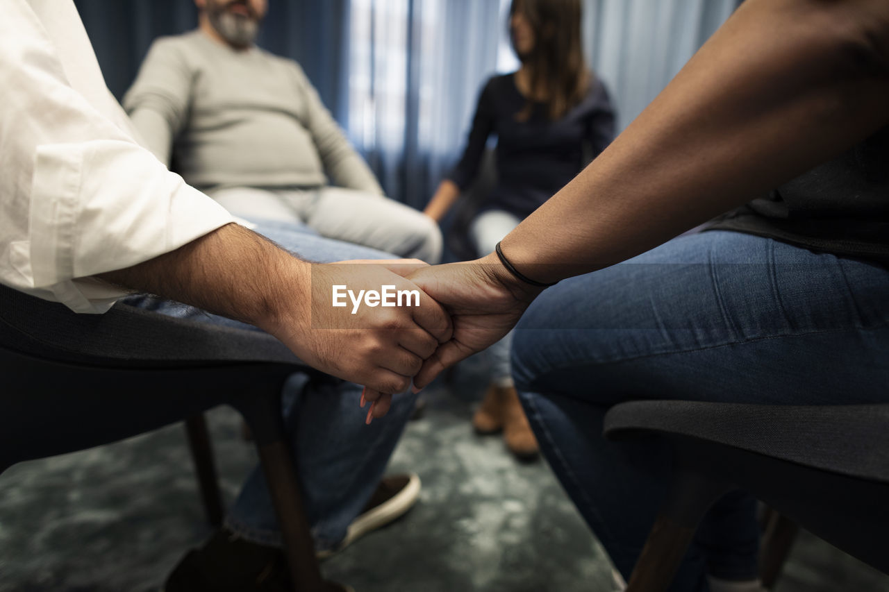Mid section of people holding hands during therapy