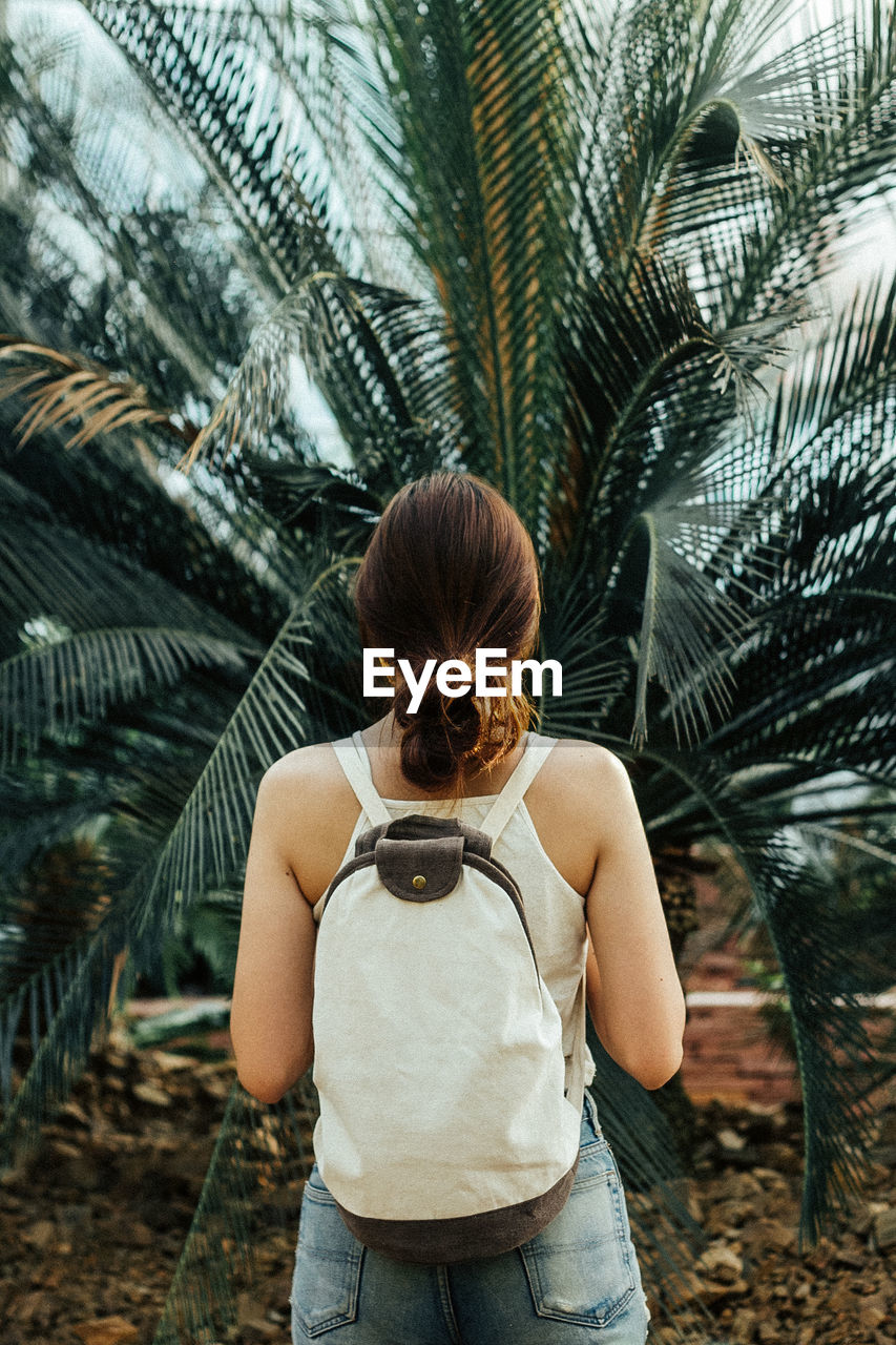 REAR VIEW OF WOMAN STANDING ON PALM TREES