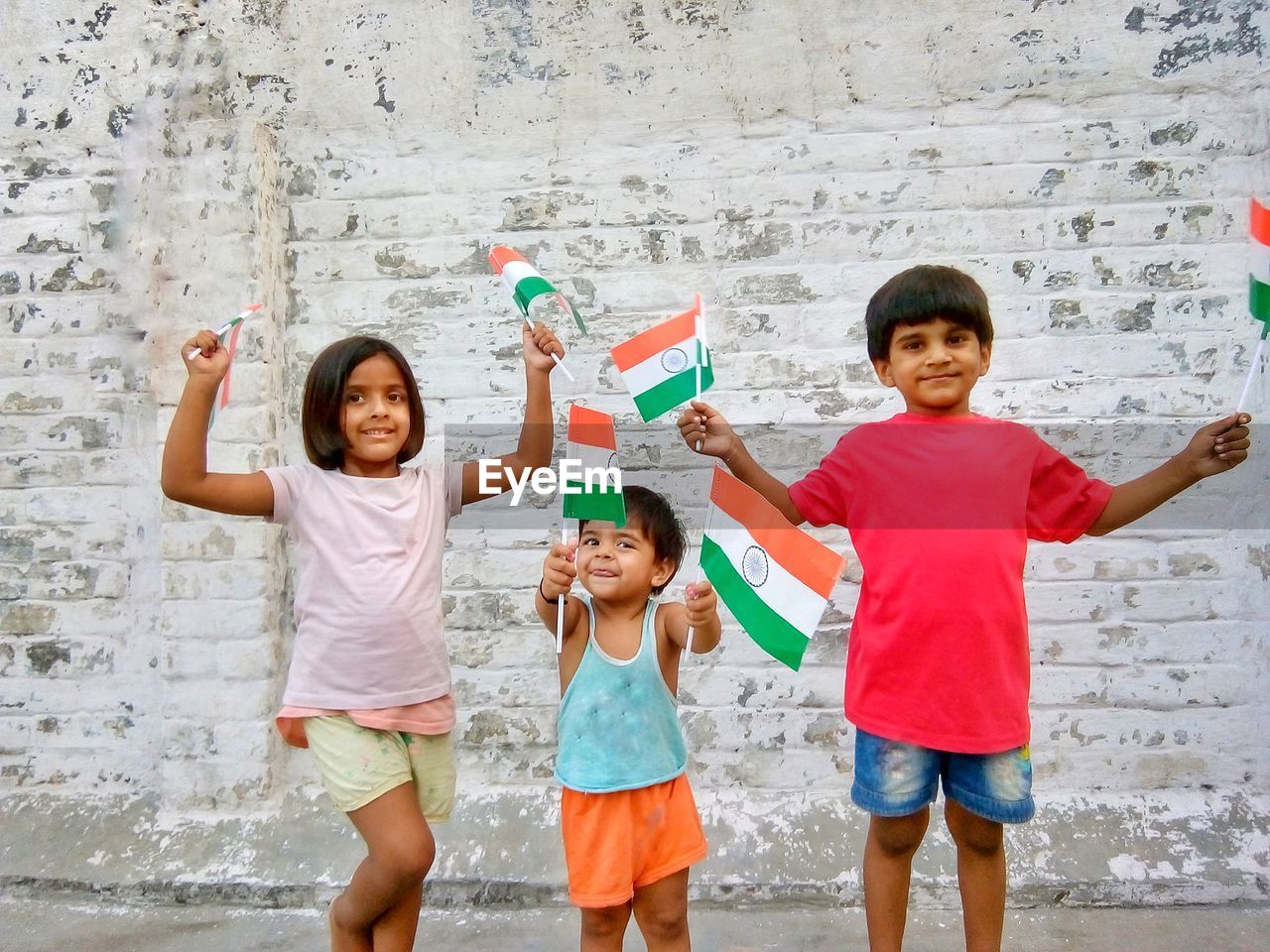 Portrait of happy children with indian flags standing against wall