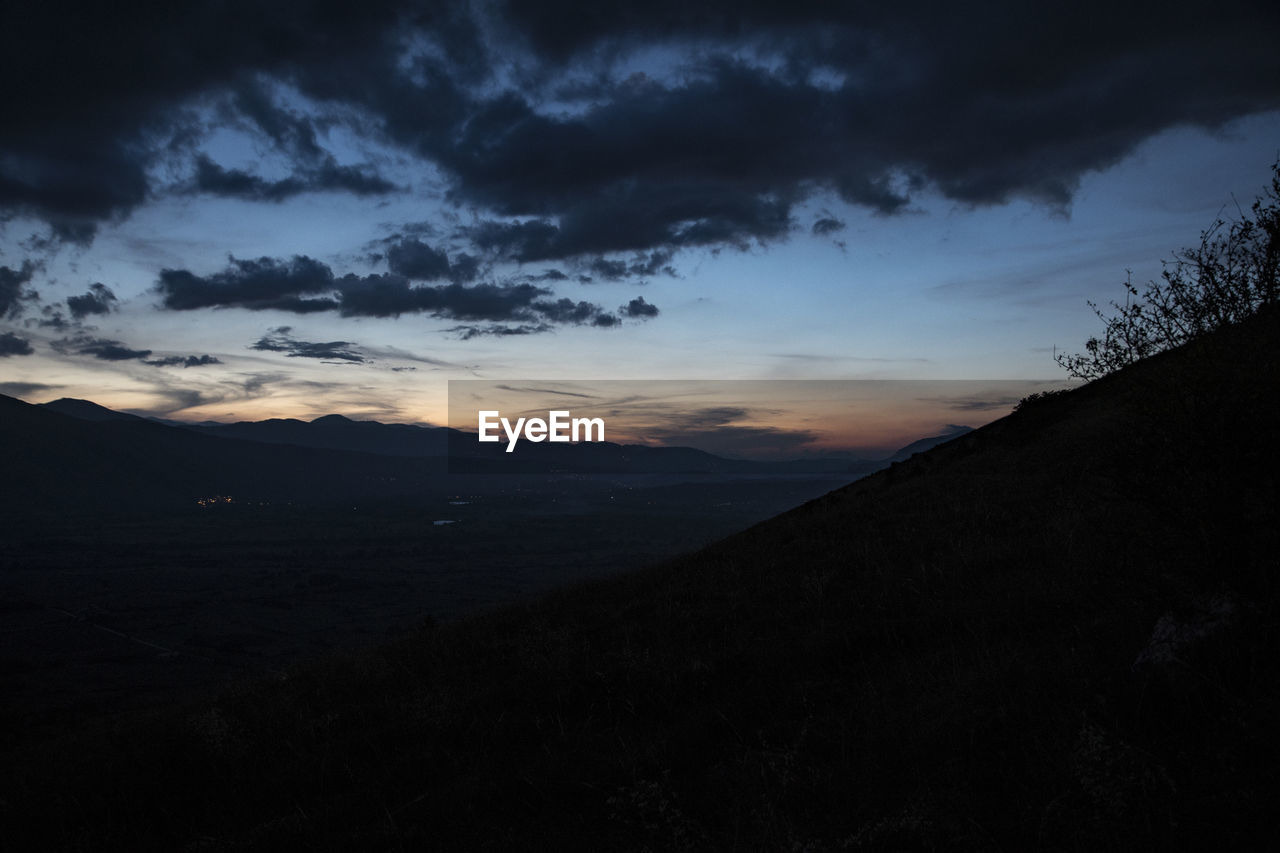 SCENIC VIEW OF SILHOUETTE LANDSCAPE AGAINST SKY AT SUNSET