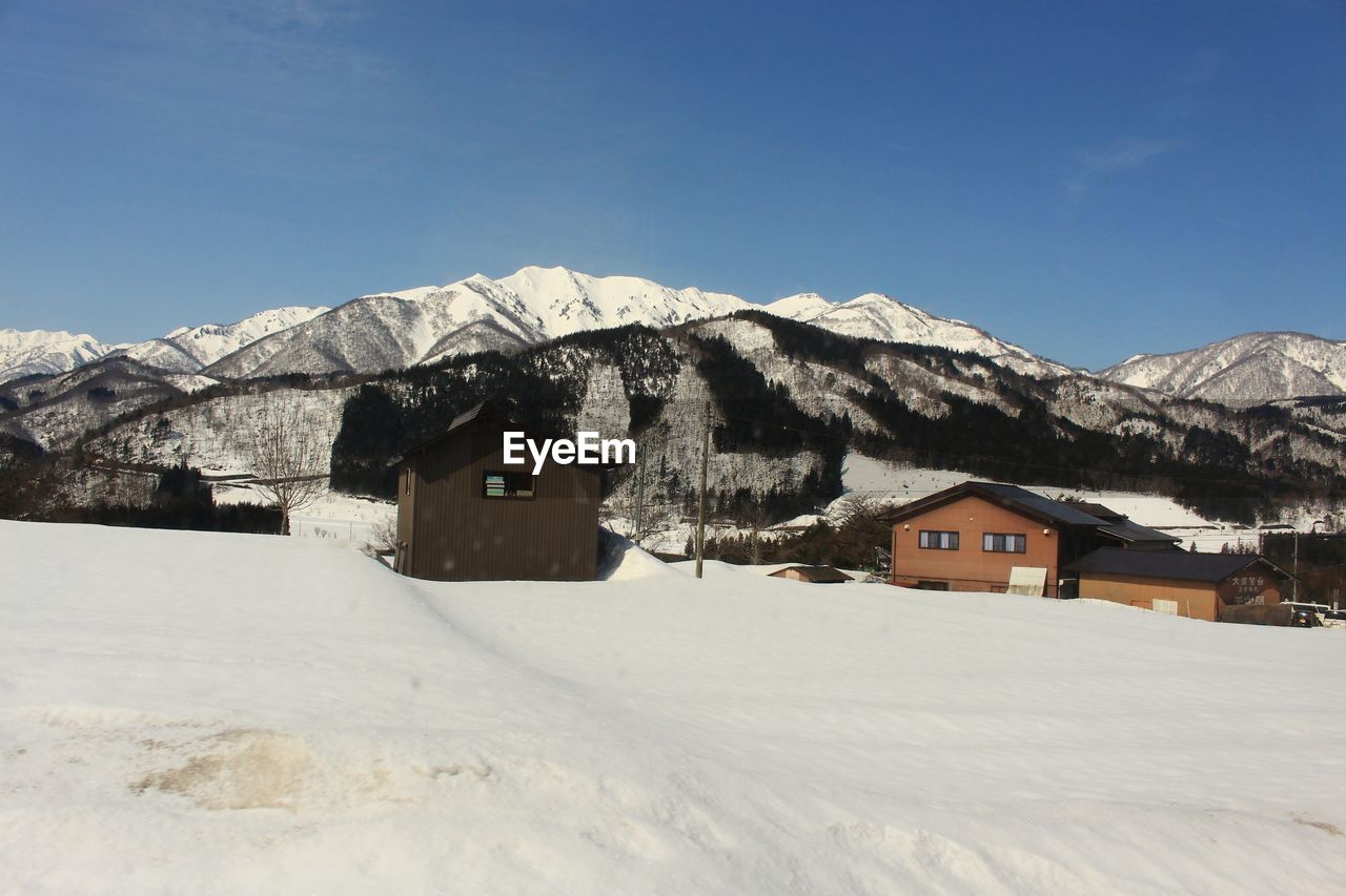 HOUSES ON SNOWCAPPED MOUNTAINS AGAINST SKY