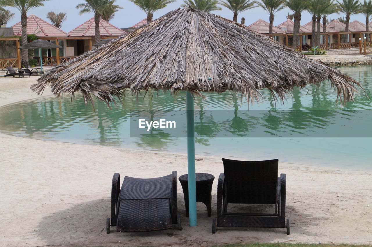 LOUNGE CHAIRS ON BEACH AGAINST SKY