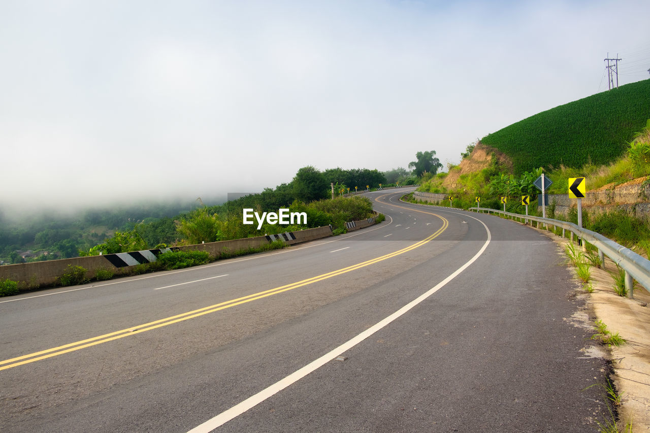 ROAD BY TREES AGAINST SKY