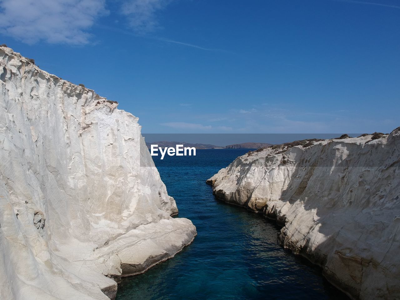 Rock formations by sea against blue sky