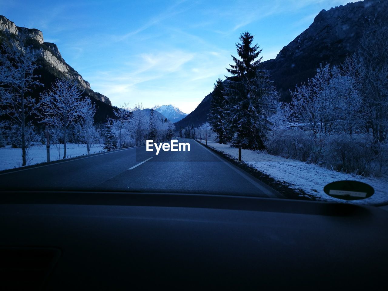 Road amidst trees against sky seen through car windshield