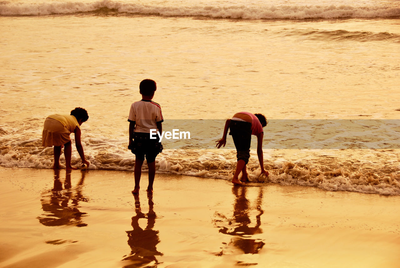 REAR VIEW OF PEOPLE ON SHORE