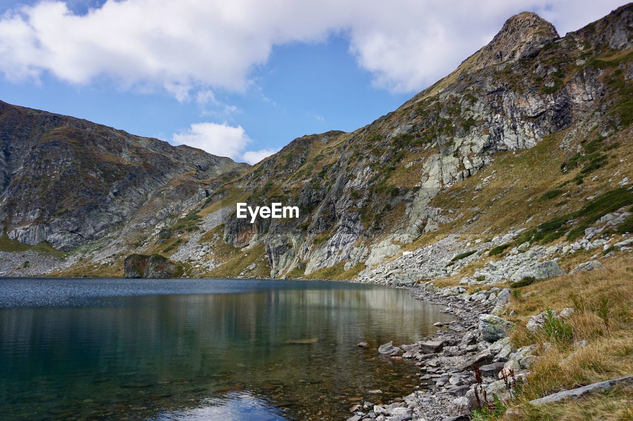 Scenic view of lake by mountains against sky