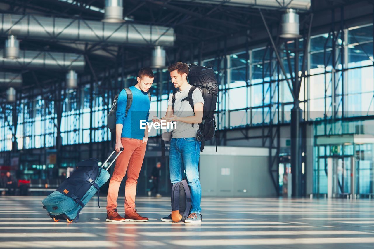 Friends talking while standing at airport