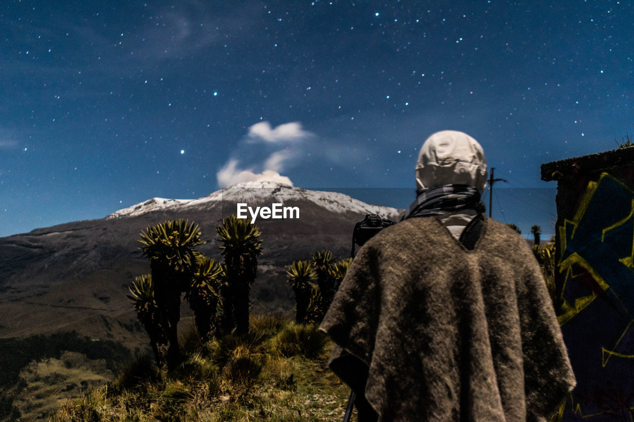 Rear view of man standing in desert against star field