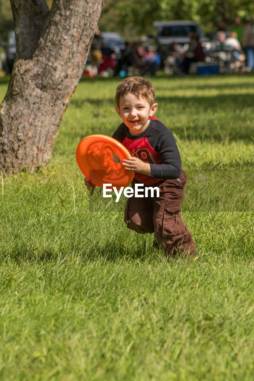 Portrait of boy playing with plastic disc on grassy field at park
