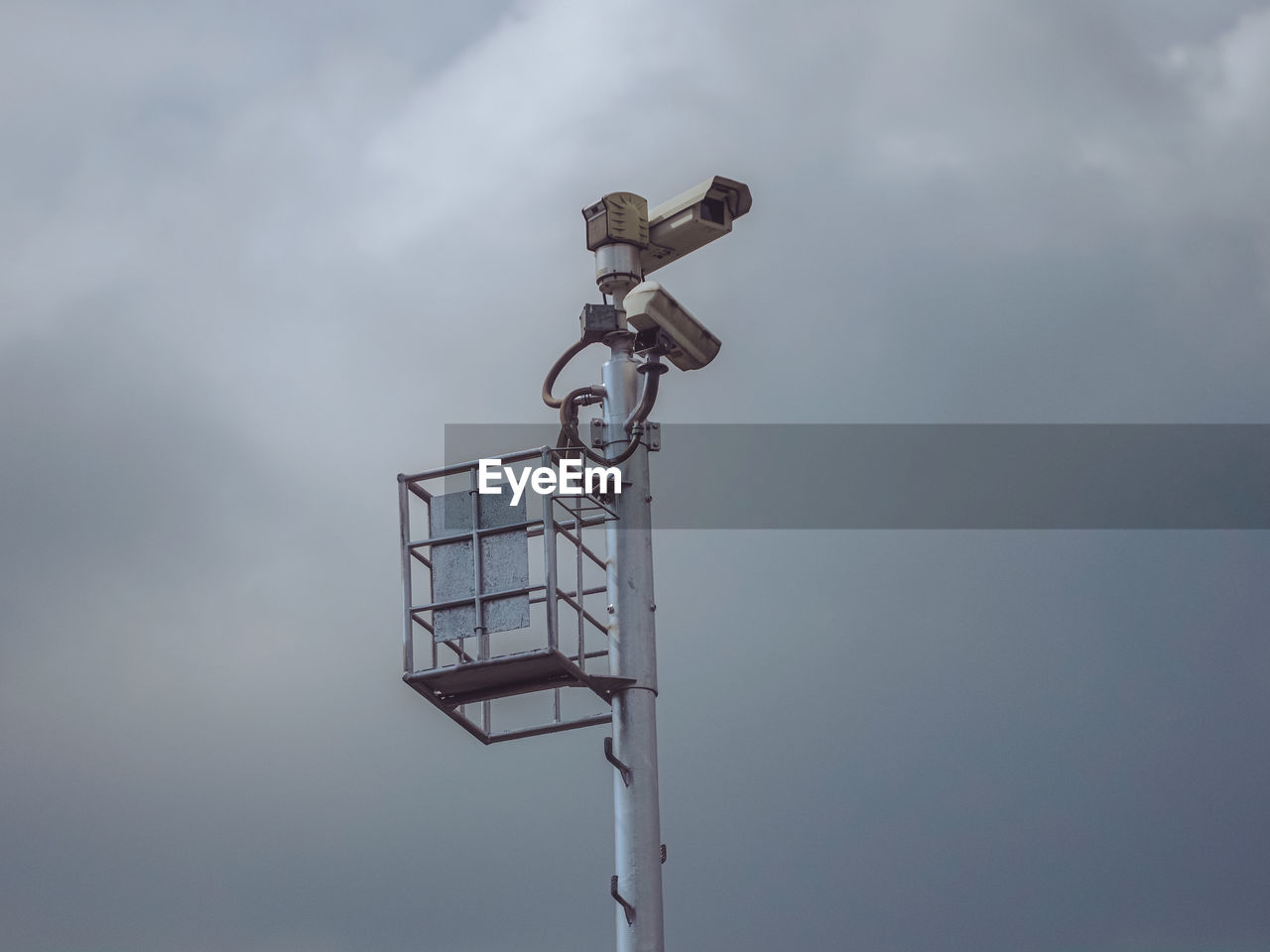 Traffic surveillance cctv camera on high tower pole and dramatic grey sky background